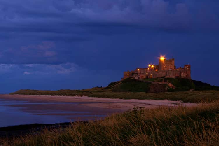 View at dawn of Bamburgh Castle from the beach and rocks