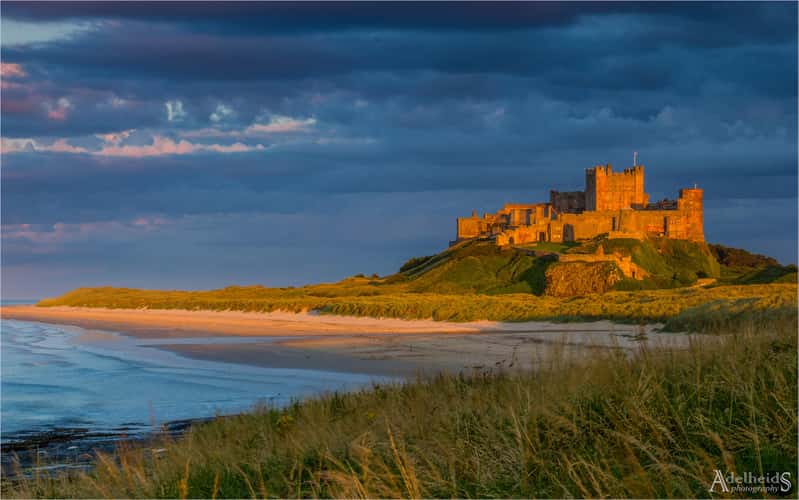 View at dawn of Bamburgh Castle from the beach and rocks