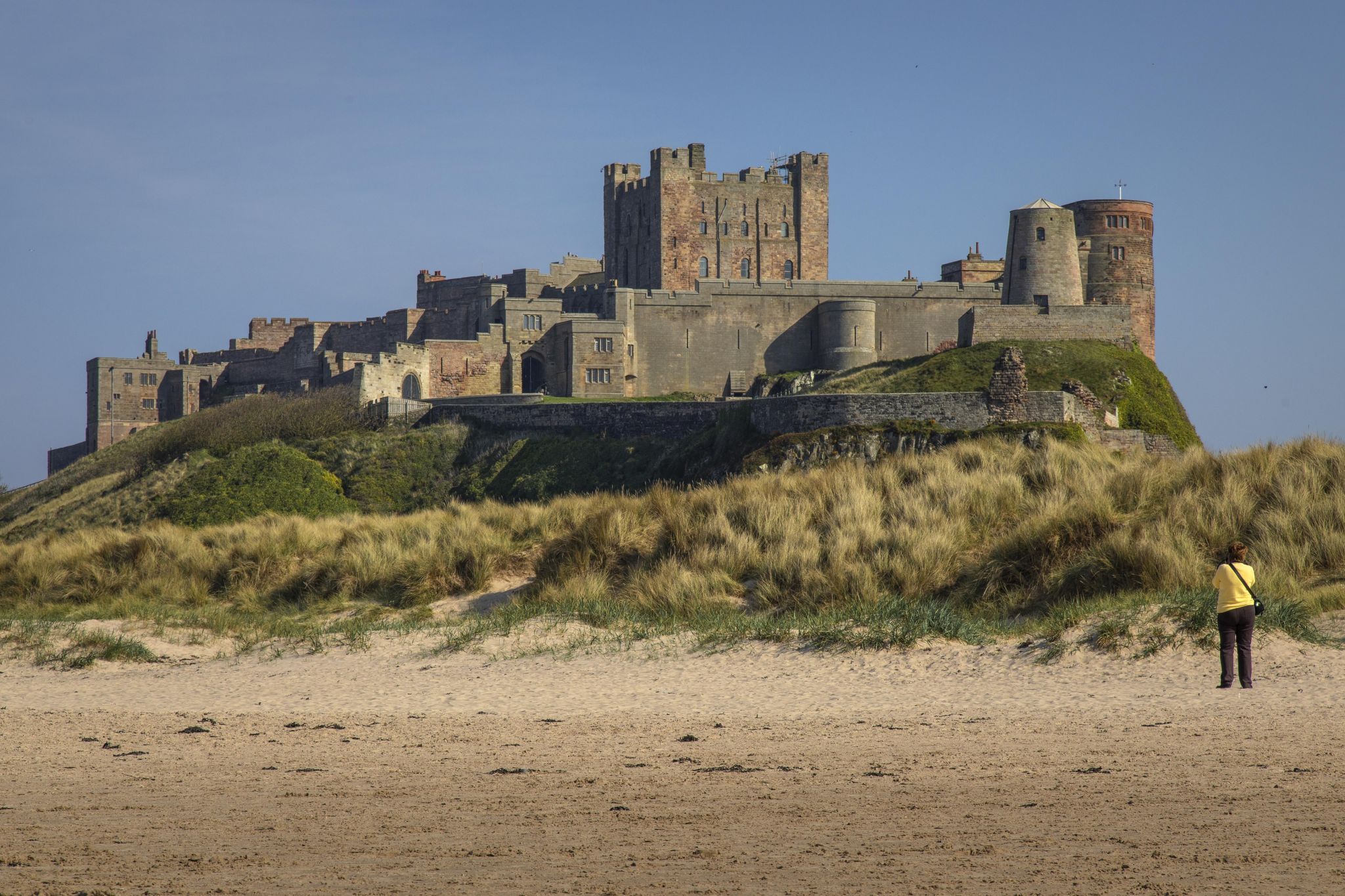 View at dawn of Bamburgh Castle from the beach and rocks, United Kingdom