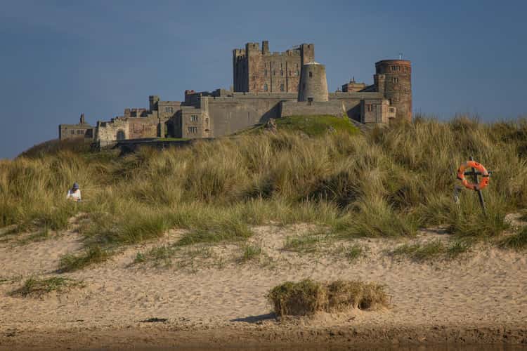 View at dawn of Bamburgh Castle from the beach and rocks