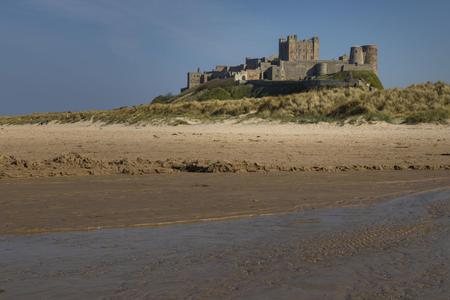 View at dawn of Bamburgh Castle from the beach and rocks