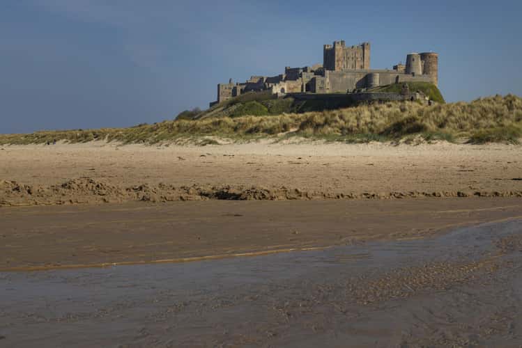 View at dawn of Bamburgh Castle from the beach and rocks
