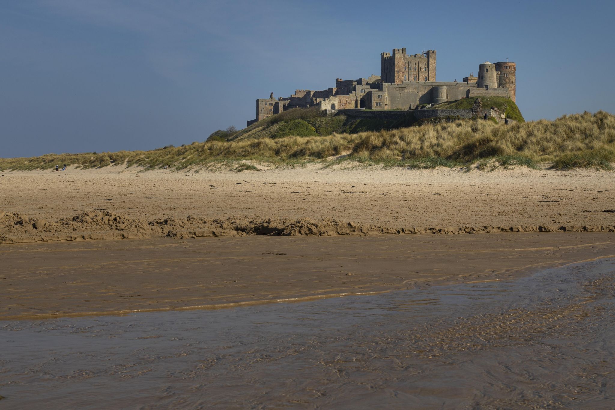 View at dawn of Bamburgh Castle from the beach and rocks, United Kingdom