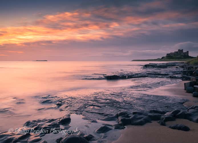 View at dawn of Bamburgh Castle from the beach and rocks