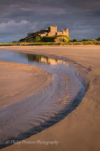 View at dawn of Bamburgh Castle from the beach and rocks