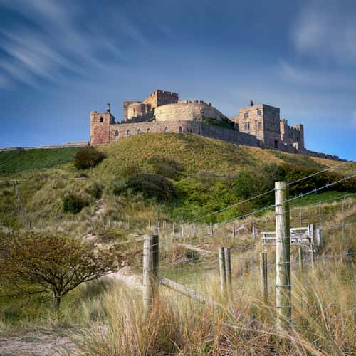 View at dawn of Bamburgh Castle from the beach and rocks