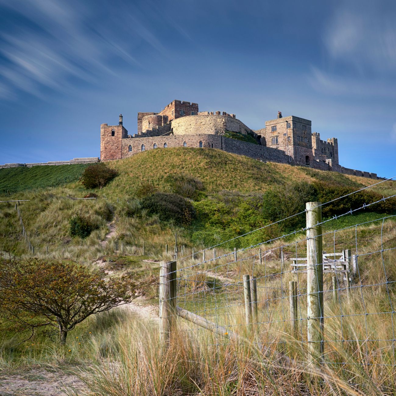 View at dawn of Bamburgh Castle from the beach and rocks, United Kingdom
