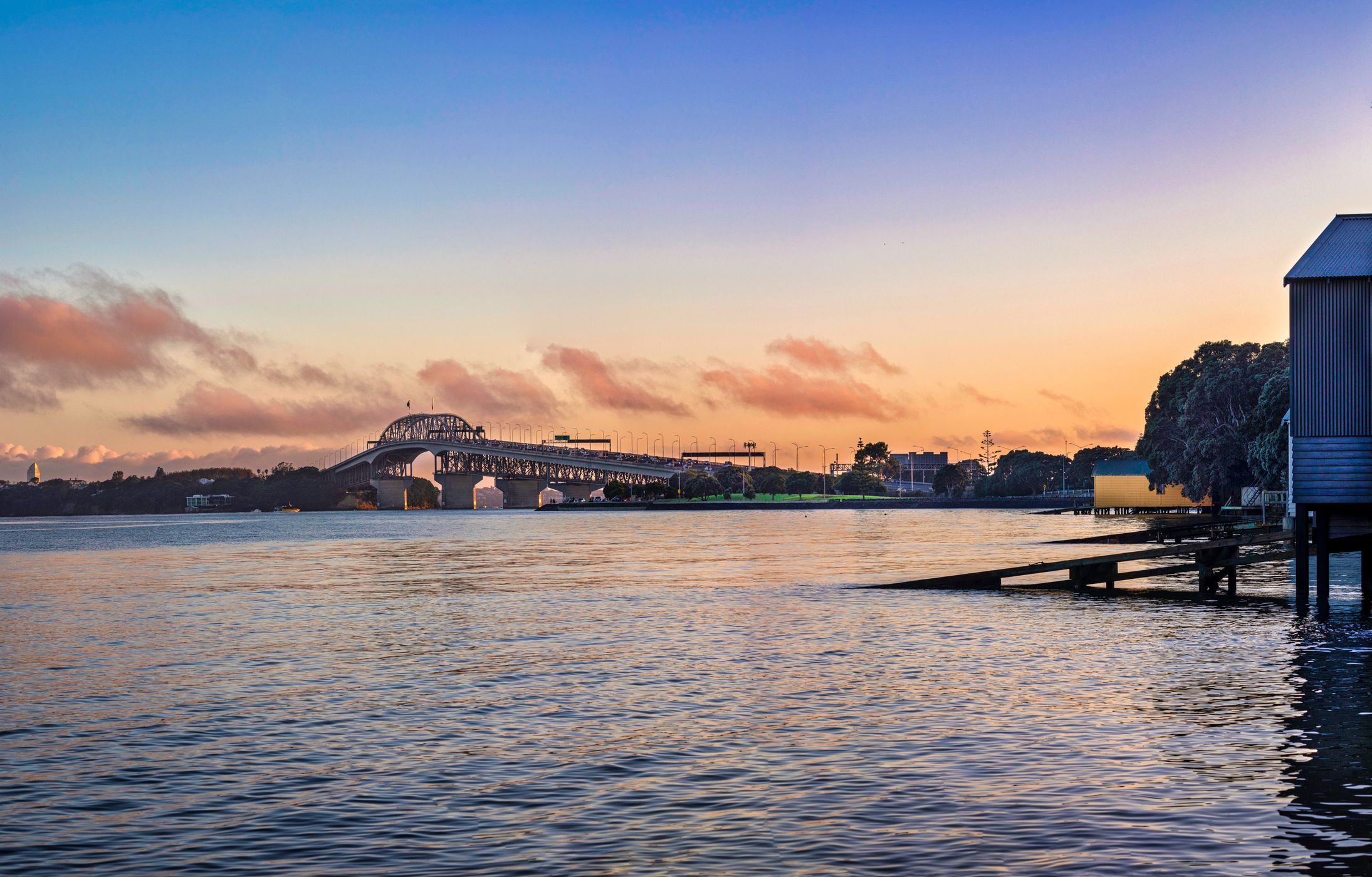 Auckland Harbour bridge & boat houses, Sentinel Rd Beach, New Zealand