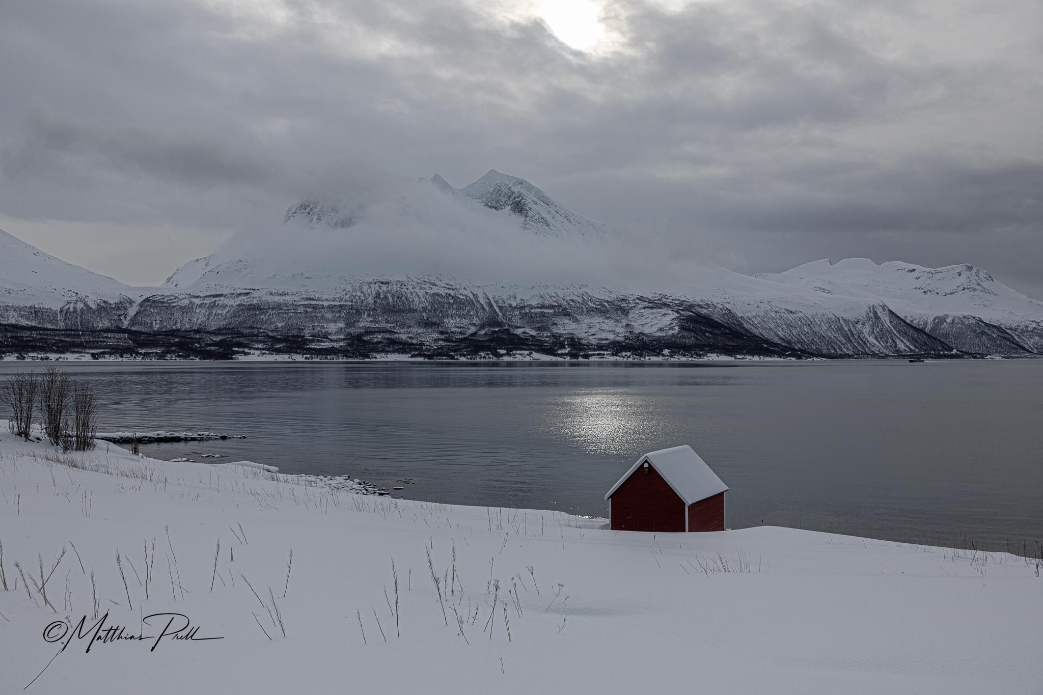 Red hut in front of fjord and mountain, Straumsbukta, Norway