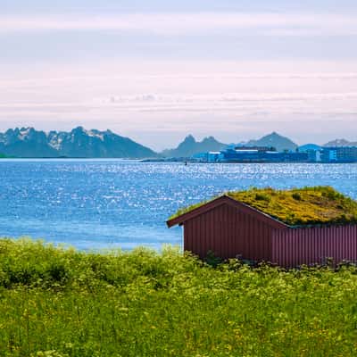 a hut, some grass and water with mountains, Norway